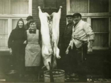 Gerrit Hilbrands (rechts) beoefende naast de boerderij ook het vak van huisslachter. Hier aan het werk bij de familie